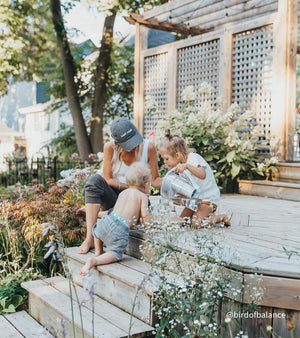@birdofbalance A mom on her backyard deck watching one of her kids fill a glass of water with her white Santevia MINA Alkaline Pitcher
