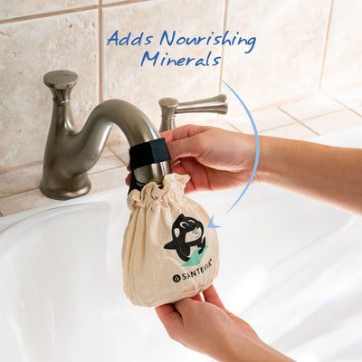 A Santevia Bath Filter hanging on a bath tub faucet with an arrow highlighting that it adds nourishing minerals.