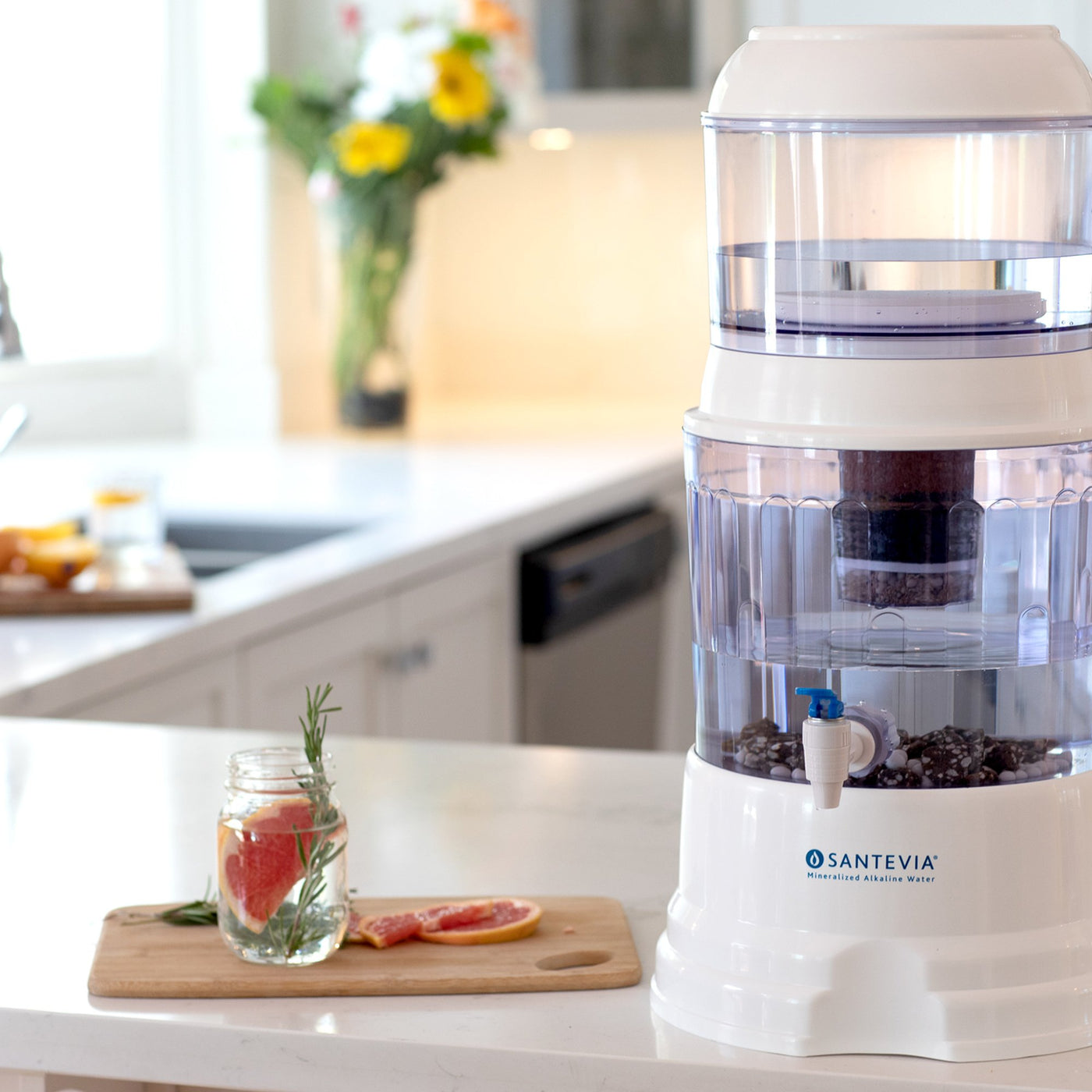 The Santevia Gravity Water System in a kitchen with a glass of alkaline water infused with grapefruit and rosemary